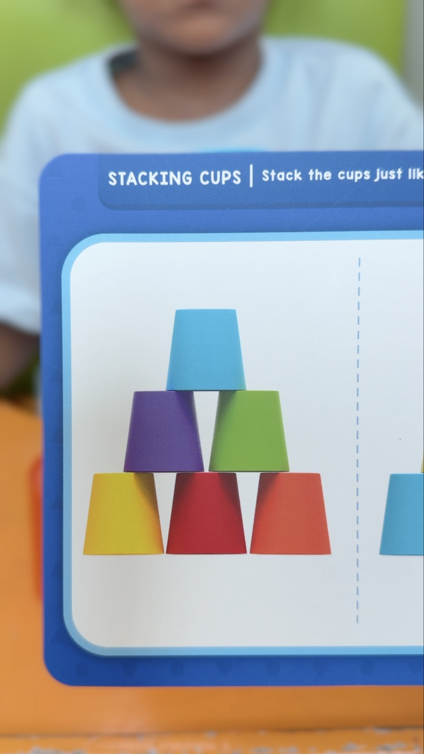 Stacking cups activity card showing a colorful cup pyramid used for visual-motor skill development in children.
